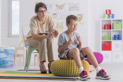 little emotional boy being aggressive during therapy session with child psychotherapist