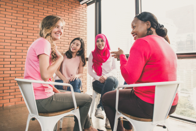 women wearing pink color clothes sitting in circle talking